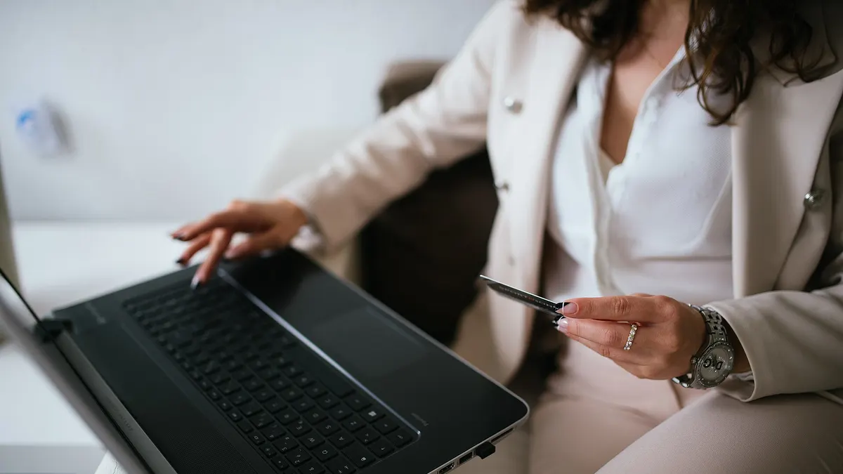 Pessoa comprando on-line pelo notebook com um cartão