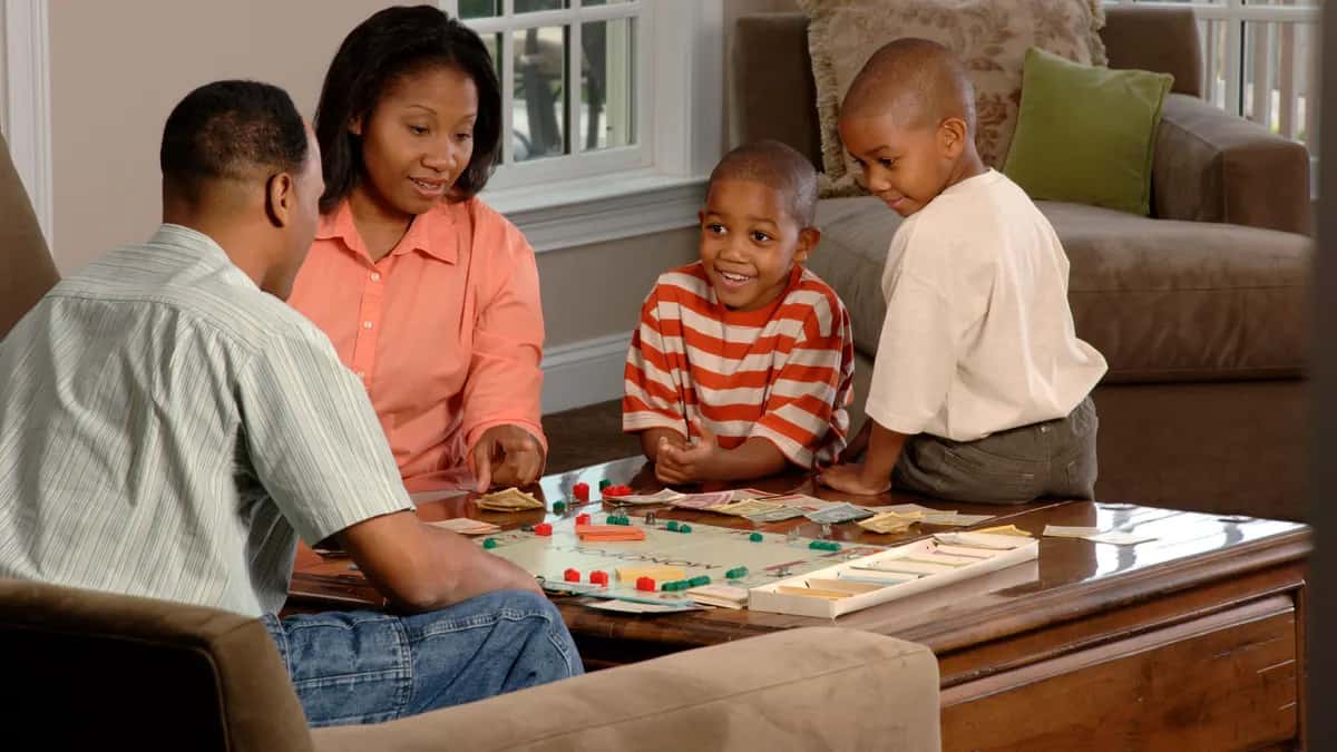 Una familia juega un juego de mesa en el living de su casa