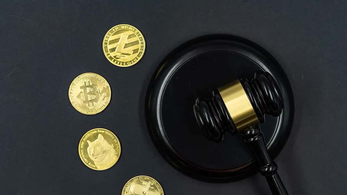 Coins with cryptocurrency logos next to a judge's gavel