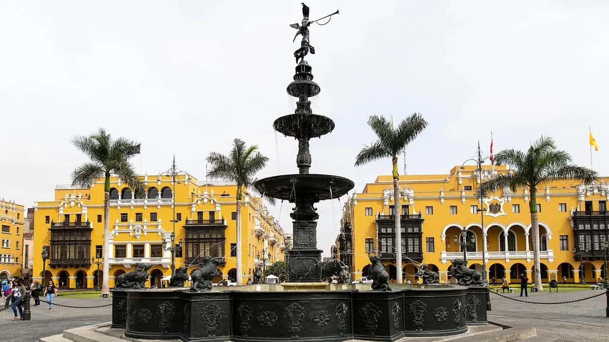 Bronze fountain in Lima's Plaza Mayor with yellow colonial buildings